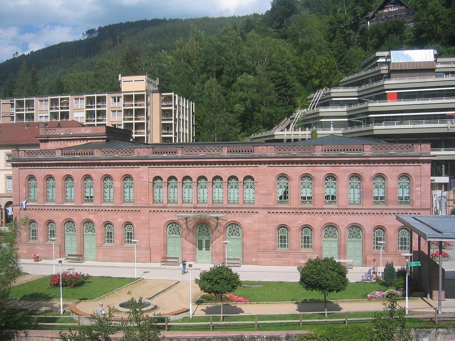 Das Palais Thermal in Bad Wildbad: historischer Sandsteinbau mit Rundbogenfenstern, davor ein Garten, dahinter bewaldete Hänge